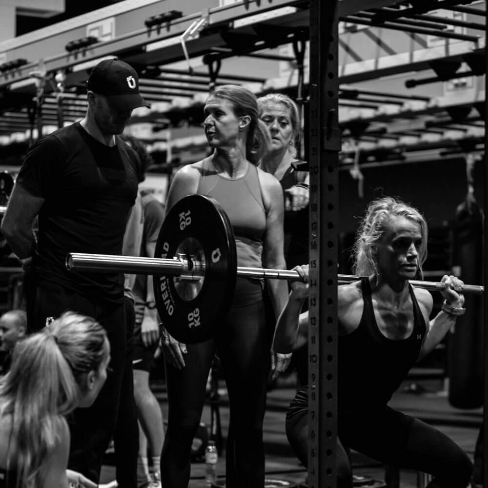 A group of people doing squats in a gym.