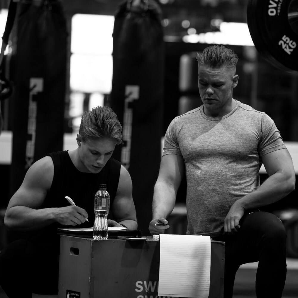 Two men sitting at a table in a gym.